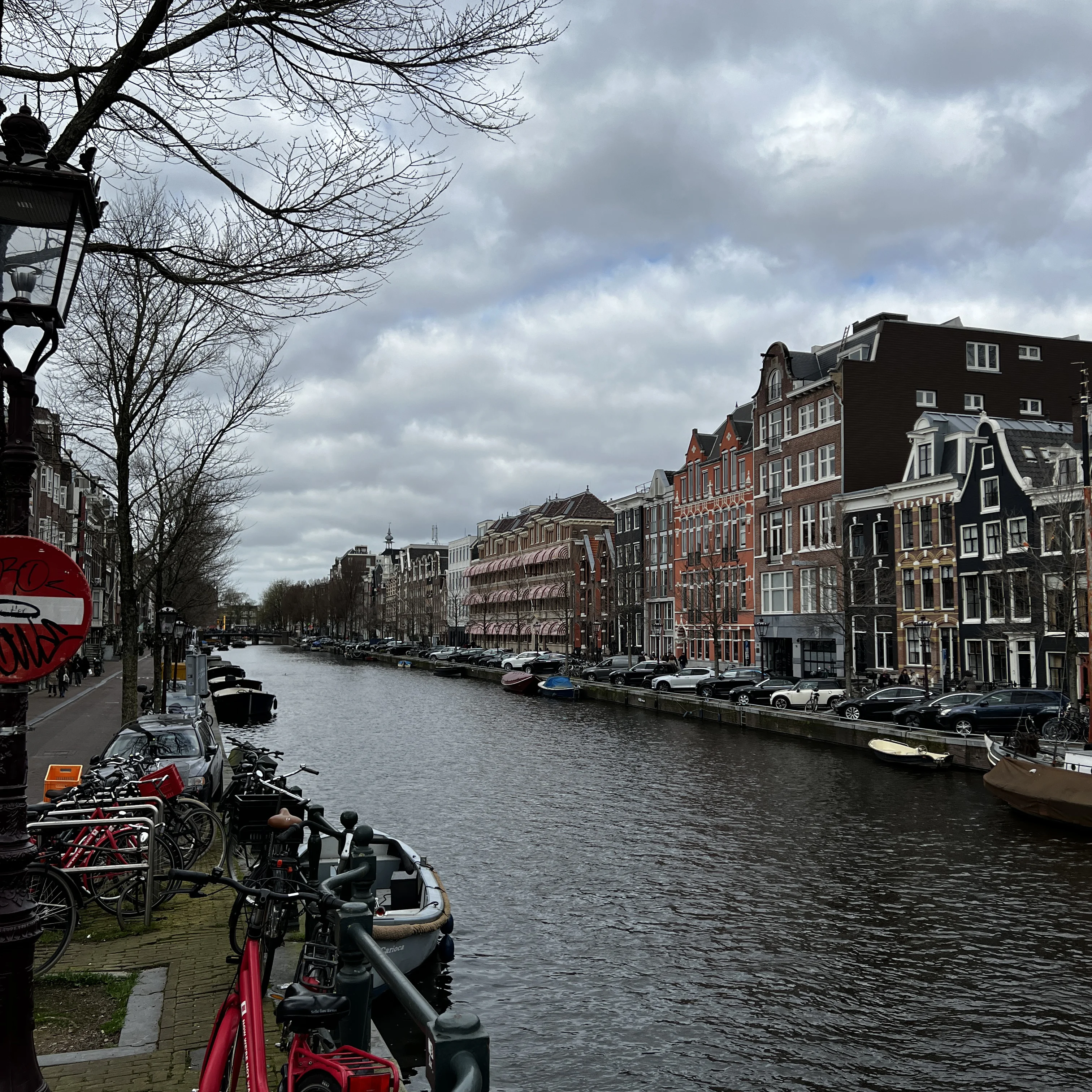 A wide canal in Amsterdam with pastel buildings and sunlight.